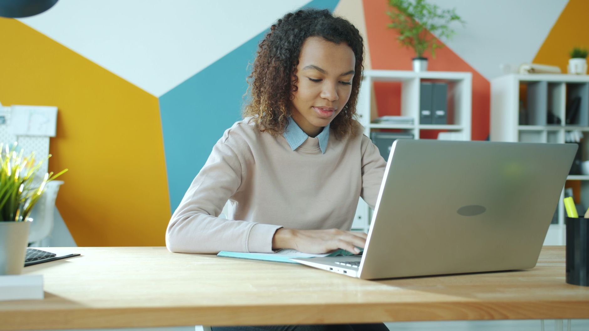 Young woman focused on work at a modern office, using laptop.